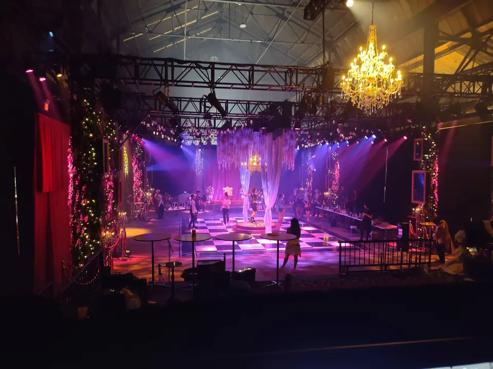 The Queen's Ball ballroom set, chandelier and candelabras washed in violet and red light