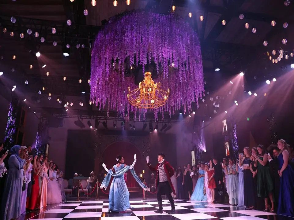 Guests beneath a cascading crystal chandelier in the Queen's Ball ballroom