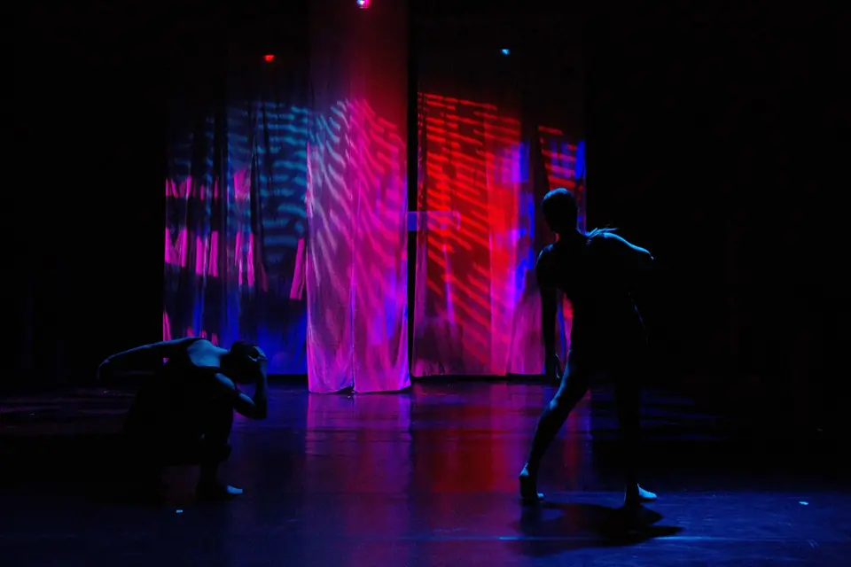 A dancer mid-movement against a wall of saturated magenta and violet light
