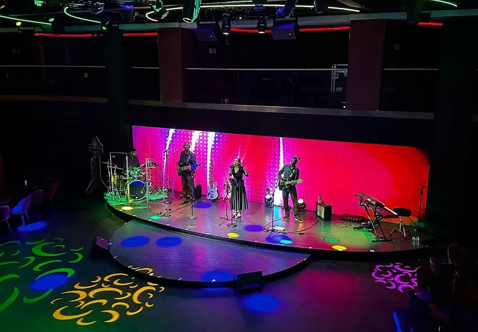 A Brazilian samba band performing on a lounge stage aboard MSC Seashore, red LED wall behind them
